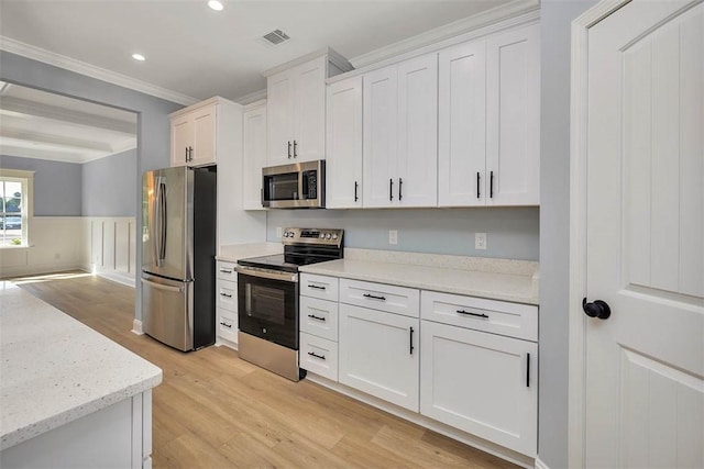 117 Rachel Way, Brunswick, GA 31523 - kitchen with stainless steel appliances, light wood-type flooring, crown molding, white cabinetry, and wainscoting