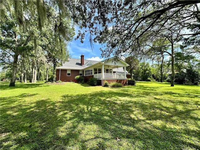 1457 N River Oaks Dr, Blackshear, GA 31516 - back of house featuring a chimney, a yard, brick siding, and covered porch