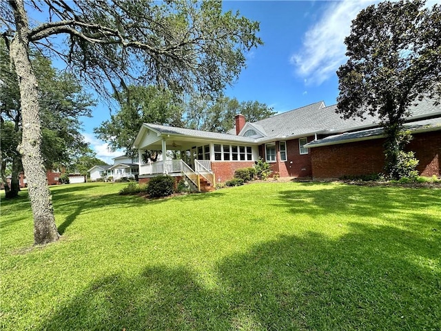 1457 N River Oaks Dr, Blackshear, GA 31516 - rear view of property with covered porch, a chimney, brick siding, and a yard