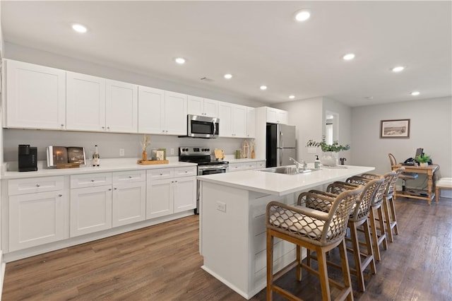 kitchen featuring white cabinets, stainless steel appliances, a center island with sink, and a breakfast bar area