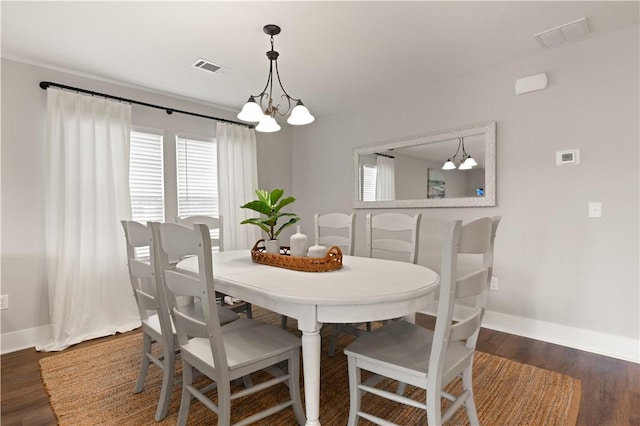 dining space featuring dark hardwood / wood-style flooring and an inviting chandelier