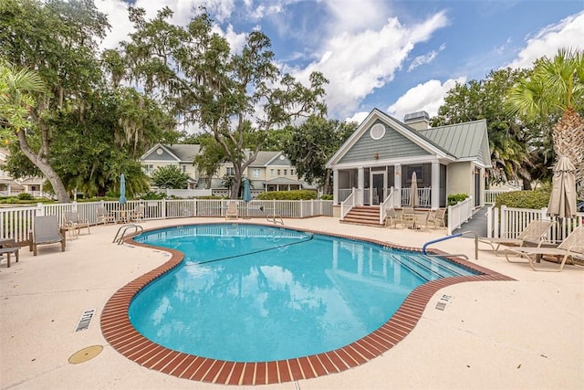 community pool featuring a sunroom, fence, and a patio area