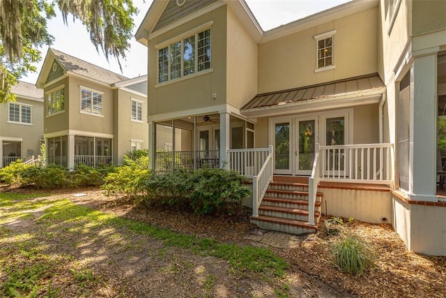 back of property featuring a standing seam roof, stucco siding, and metal roof