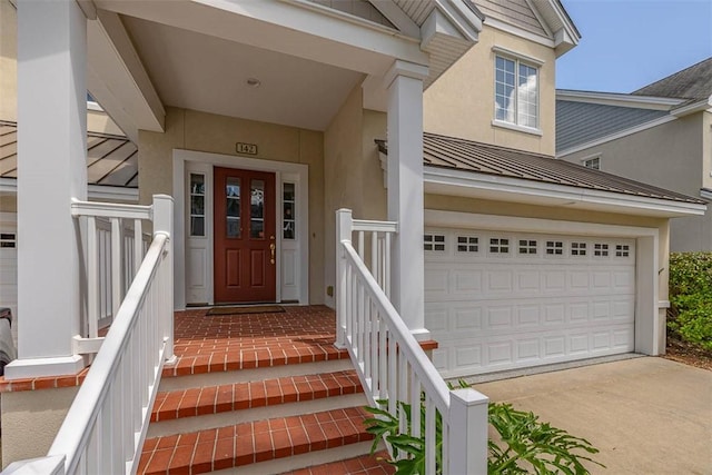 doorway to property with stucco siding, metal roof, a standing seam roof, concrete driveway, and an attached garage