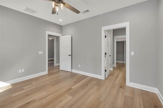 unfurnished bedroom featuring ceiling fan, light wood-type flooring, and a textured ceiling