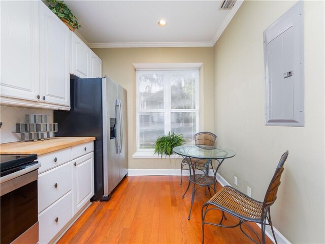 1106 Plantation Point Dr, Saint Simons Island, GA 31522 - kitchen featuring electric panel, appliances with stainless steel finishes, white cabinetry, decorative backsplash, and ornamental molding