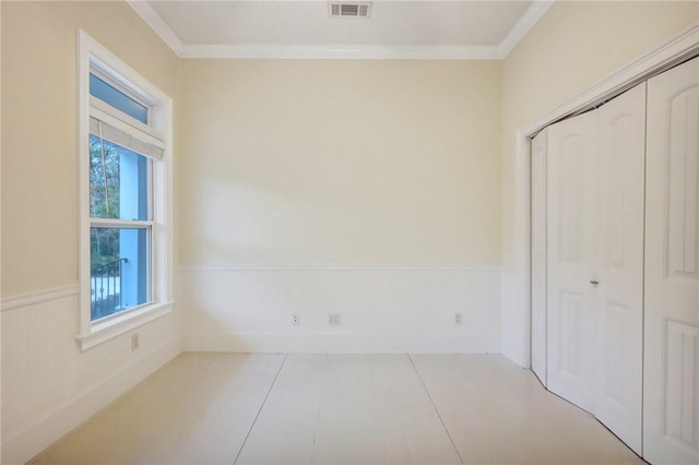 unfurnished bedroom with multiple windows, light tile patterned floors, crown molding, and a closet