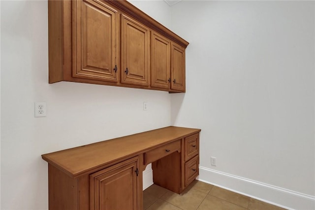 unfurnished office featuring built in desk and light tile patterned floors