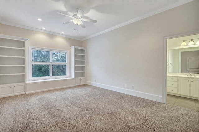 unfurnished bedroom with sink, ceiling fan, ensuite bathroom, ornamental molding, and light carpet