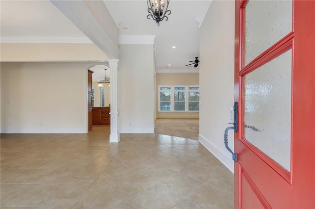 entryway featuring ceiling fan with notable chandelier, ornamental molding, light colored carpet, and ornate columns