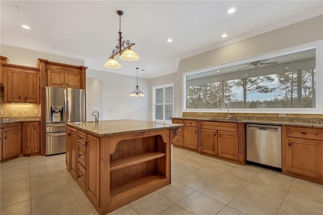 kitchen featuring sink, hanging light fixtures, an island with sink, stainless steel appliances, and light stone countertops