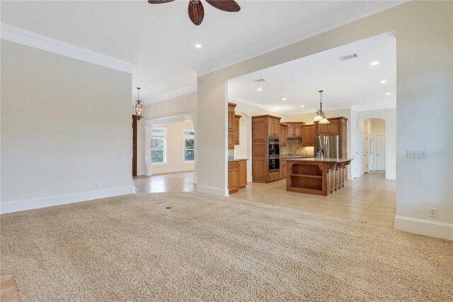 unfurnished living room with crown molding, ceiling fan, and light carpet