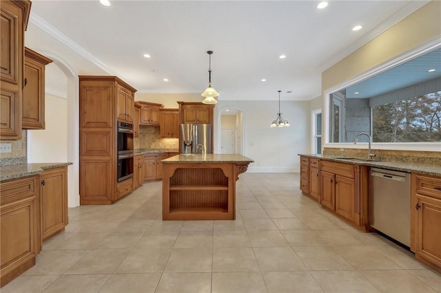 kitchen with decorative light fixtures, an island with sink, sink, stainless steel appliances, and crown molding