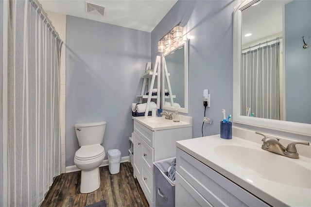 1000 Mallery Street Ext Unit G62, Saint Simons Island, GA 31522 - bathroom featuring toilet, two vanities, wood finished floors, a shower with shower curtain, and baseboards