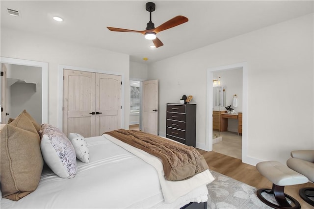 bedroom featuring ceiling fan, a closet, light hardwood / wood-style flooring, and ensuite bath