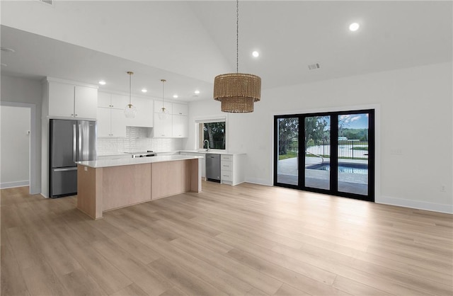 kitchen with appliances with stainless steel finishes, decorative light fixtures, a center island, light hardwood / wood-style floors, and white cabinetry