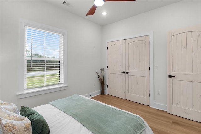 bedroom with multiple windows, ceiling fan, and light hardwood / wood-style floors