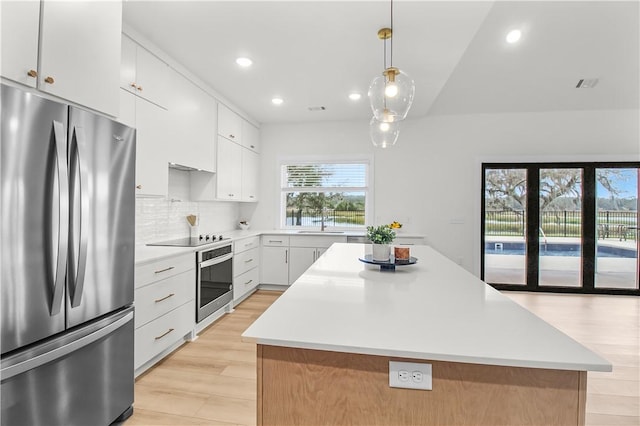 kitchen featuring decorative light fixtures, a center island, white cabinetry, and appliances with stainless steel finishes