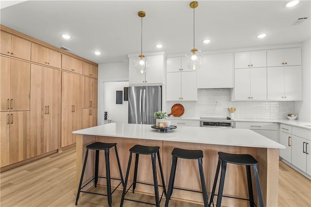 kitchen featuring white cabinets, a kitchen island, stainless steel appliances, and light hardwood / wood-style flooring