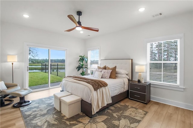 bedroom featuring a water view, light wood-type flooring, and multiple windows