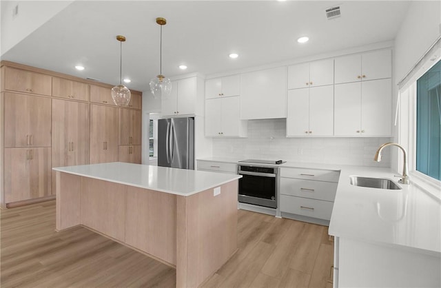 kitchen featuring light hardwood / wood-style floors, a kitchen island, white cabinetry, and appliances with stainless steel finishes