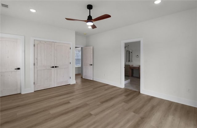 unfurnished bedroom with ensuite bath, ceiling fan, light hardwood / wood-style flooring, and two closets