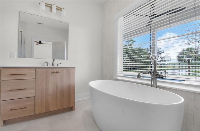 bathroom featuring tile patterned flooring, vanity, ceiling fan, and a tub