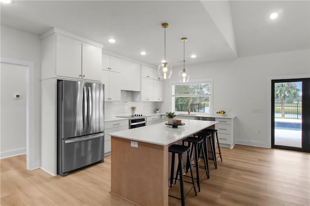 kitchen with white cabinetry, appliances with stainless steel finishes, decorative light fixtures, a kitchen island, and light wood-type flooring