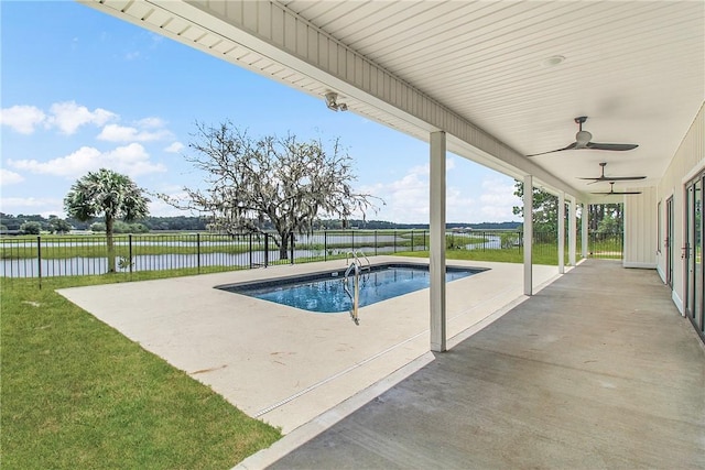 view of pool featuring ceiling fan, a yard, a water view, and a patio