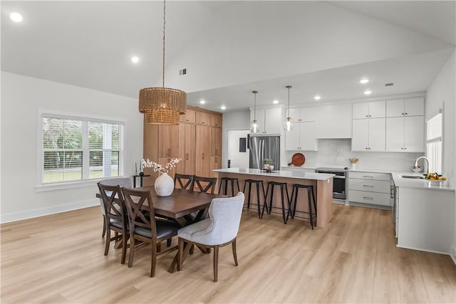 dining room with sink, high vaulted ceiling, and light wood-type flooring