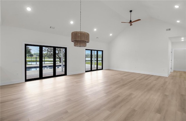 unfurnished living room with ceiling fan, high vaulted ceiling, a healthy amount of sunlight, and light wood-type flooring