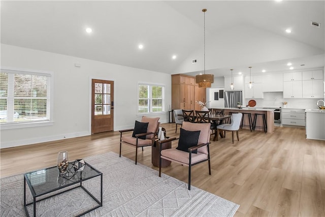 living room with light hardwood / wood-style floors, high vaulted ceiling, and sink