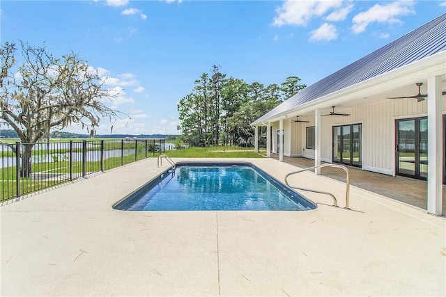 view of swimming pool with ceiling fan, a water view, and a patio