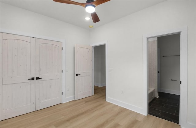 unfurnished bedroom with connected bathroom, ceiling fan, a closet, and light wood-type flooring