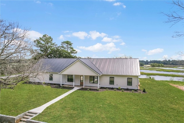 view of front of property featuring a front yard, a water view, and covered porch