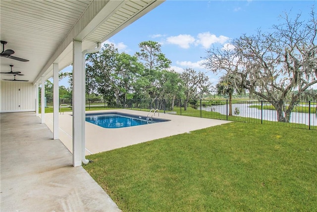 view of pool featuring a patio area, ceiling fan, a yard, and a water view