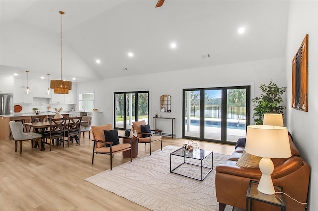 living room featuring high vaulted ceiling and light hardwood / wood-style flooring