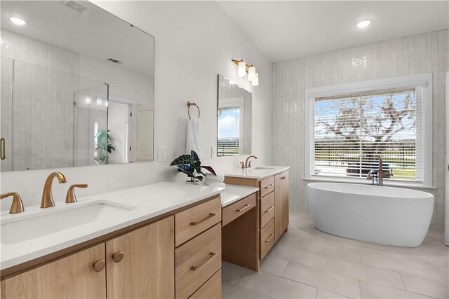 bathroom with tile patterned flooring, vanity, a tub to relax in, and tile walls