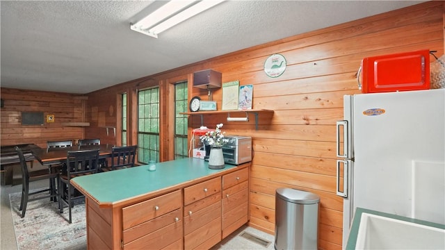 500 Altamaha Rd, Jesup, GA 31545 - kitchen featuring freestanding refrigerator, wooden walls, a peninsula, a textured ceiling, and light countertops