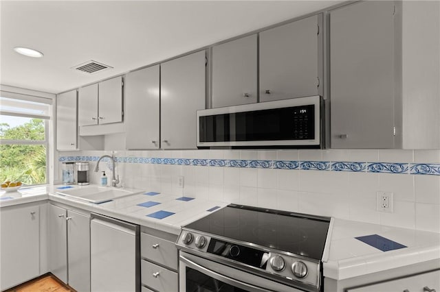 1332 Oak St Unit 9, Saint Simons Island, GA 31522 - kitchen with stainless steel range with electric cooktop, dishwashing machine, tile countertops, backsplash, and gray cabinets
