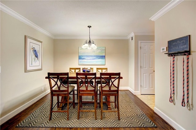 dining area with baseboards, an inviting chandelier, wood finished floors, and crown molding