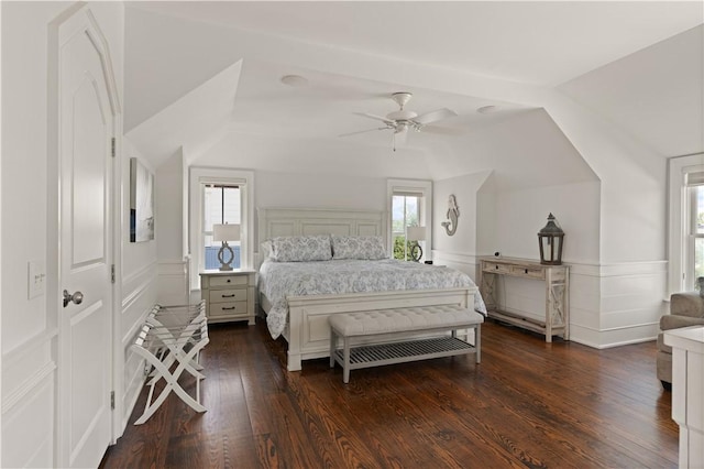 bedroom with dark wood-style flooring, ceiling fan, a wainscoted wall, and vaulted ceiling
