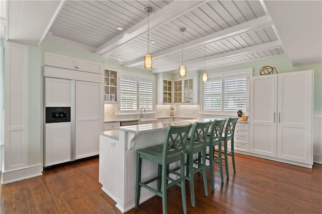 kitchen featuring beam ceiling, glass insert cabinets, dark wood-style floors, paneled fridge, and white cabinetry