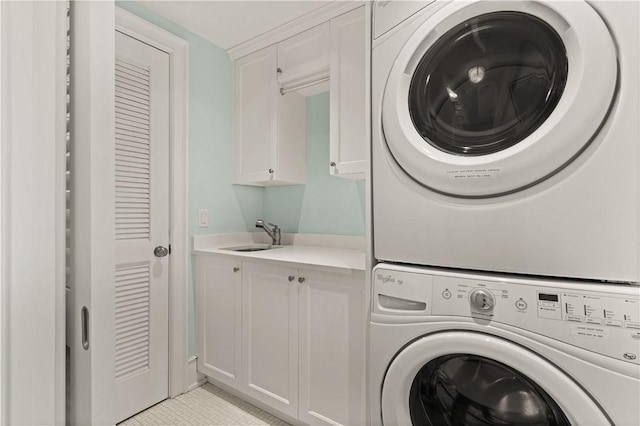 laundry area with cabinet space, a sink, and stacked washer and clothes dryer