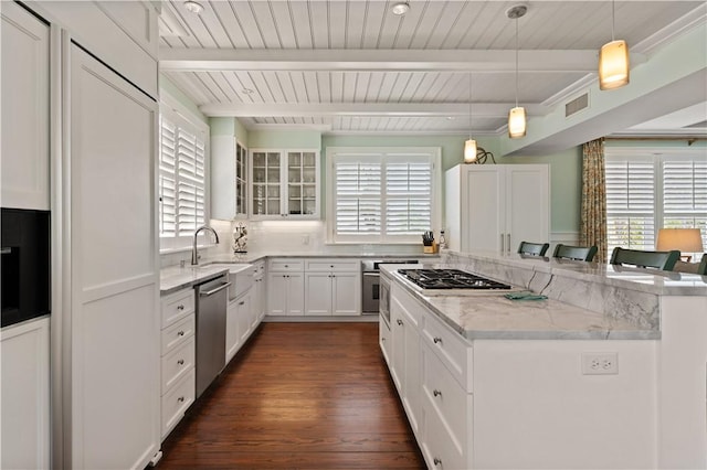 kitchen featuring a kitchen island, light stone countertops, a sink, beamed ceiling, and stainless steel appliances