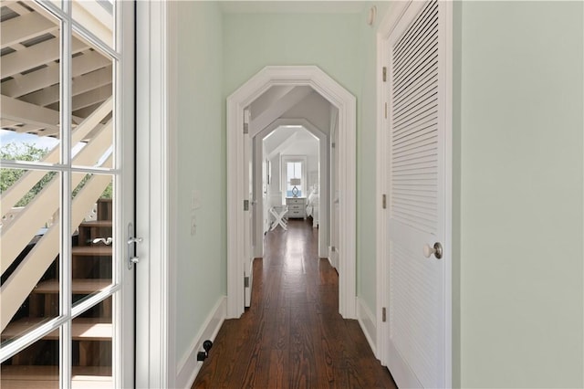 corridor featuring baseboards and dark wood-style floors