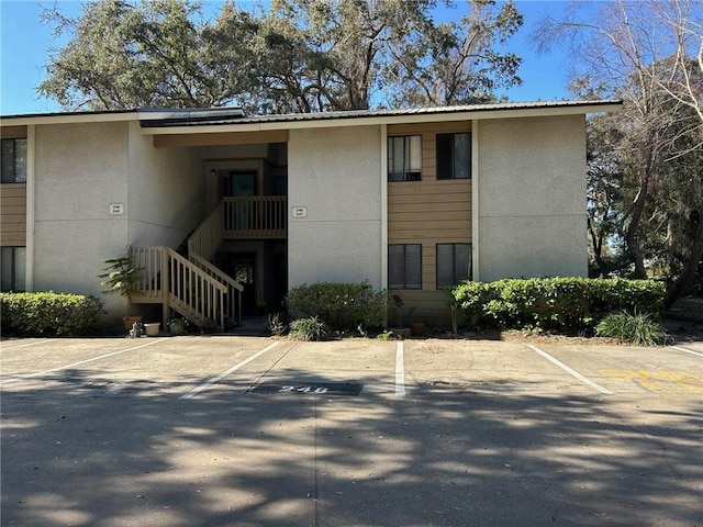 view of property featuring stairs and uncovered parking