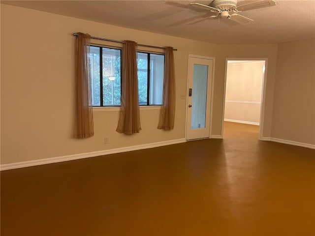 unfurnished room with a ceiling fan, finished concrete flooring, baseboards, and a textured ceiling