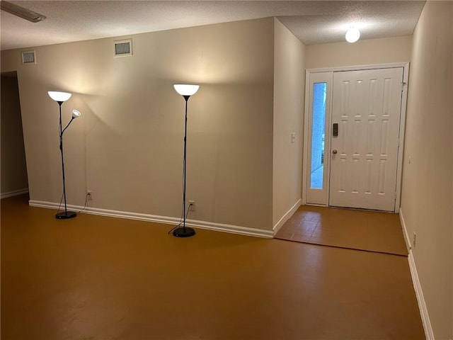 foyer with visible vents, baseboards, a textured ceiling, and concrete floors