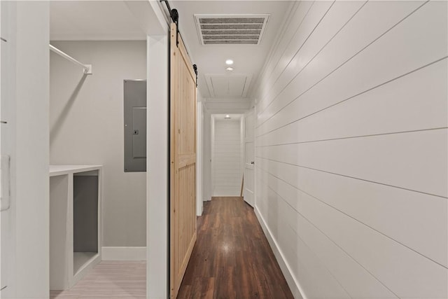 corridor with hardwood / wood-style floors, a barn door, electric panel, and wooden walls